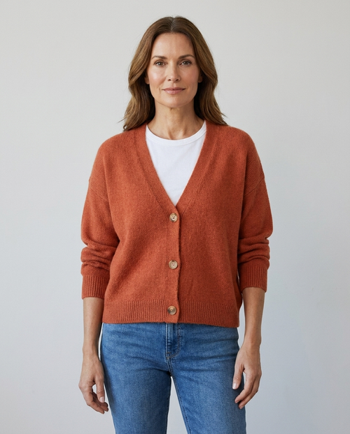 Women's relaxed knit button-front V-neck cardigan in orange, worn over a white tee with jeans